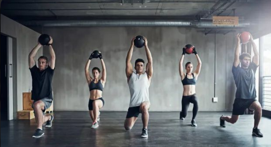 Trainer spotting a woman doing dumbbell bench press